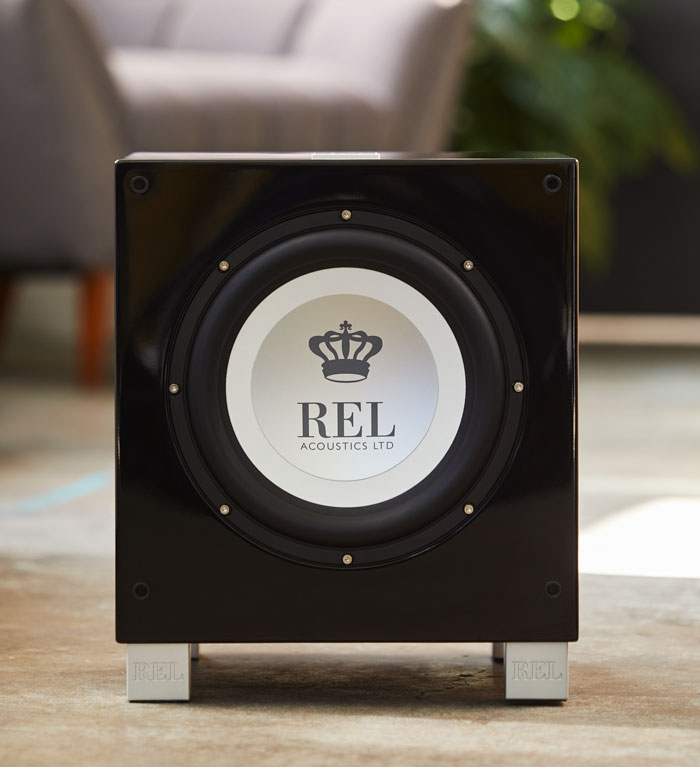 A black REL T9i Subwoofer sitting in a home on the floor